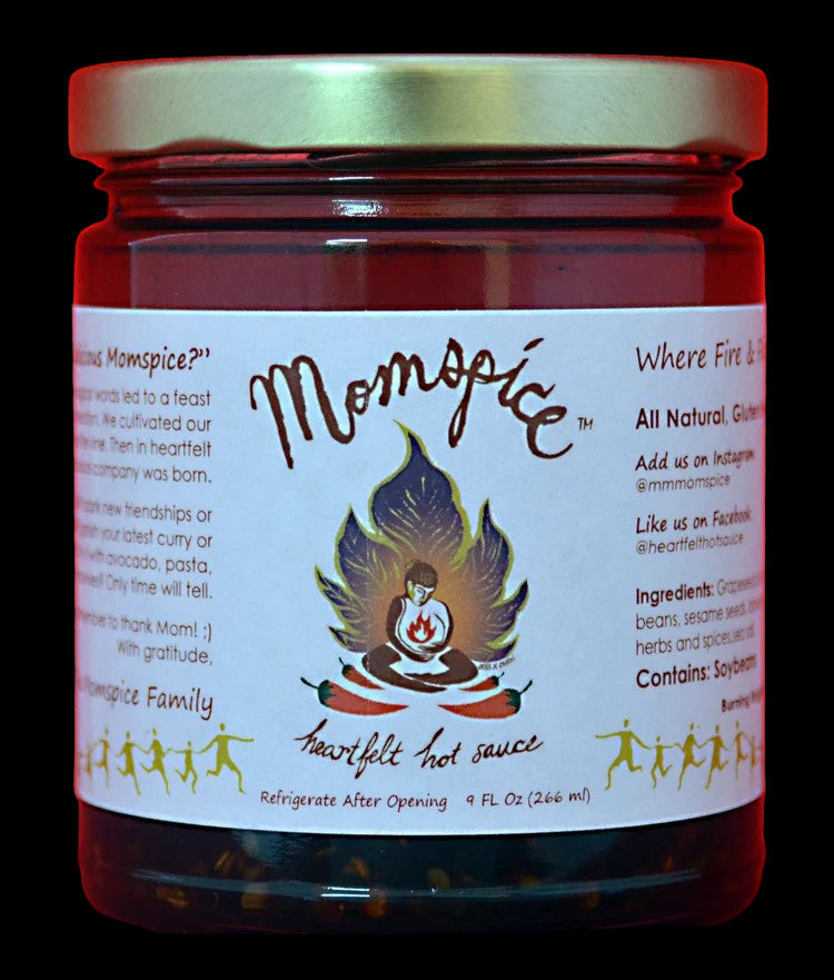 Jar of Momm spice hot sauce with a red background