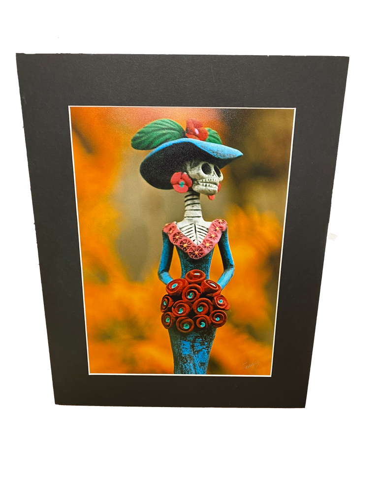 Glossy photo quality print featuring Día de los Muertos scene professionally matted with an acid free black mat board.